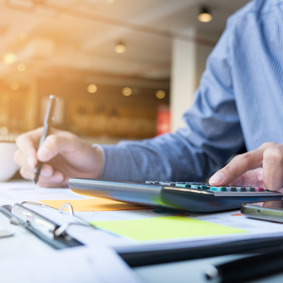 Gestor utilizando una calculadora y un bolígrafo calculando impuestos de inmuebles