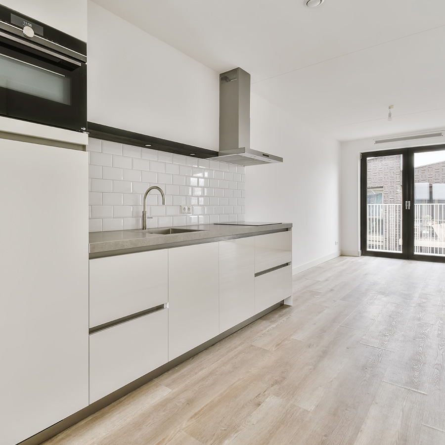 Cocina moderna con muebles blancos y suelo de madera ideal para Inversión inmobiliaria