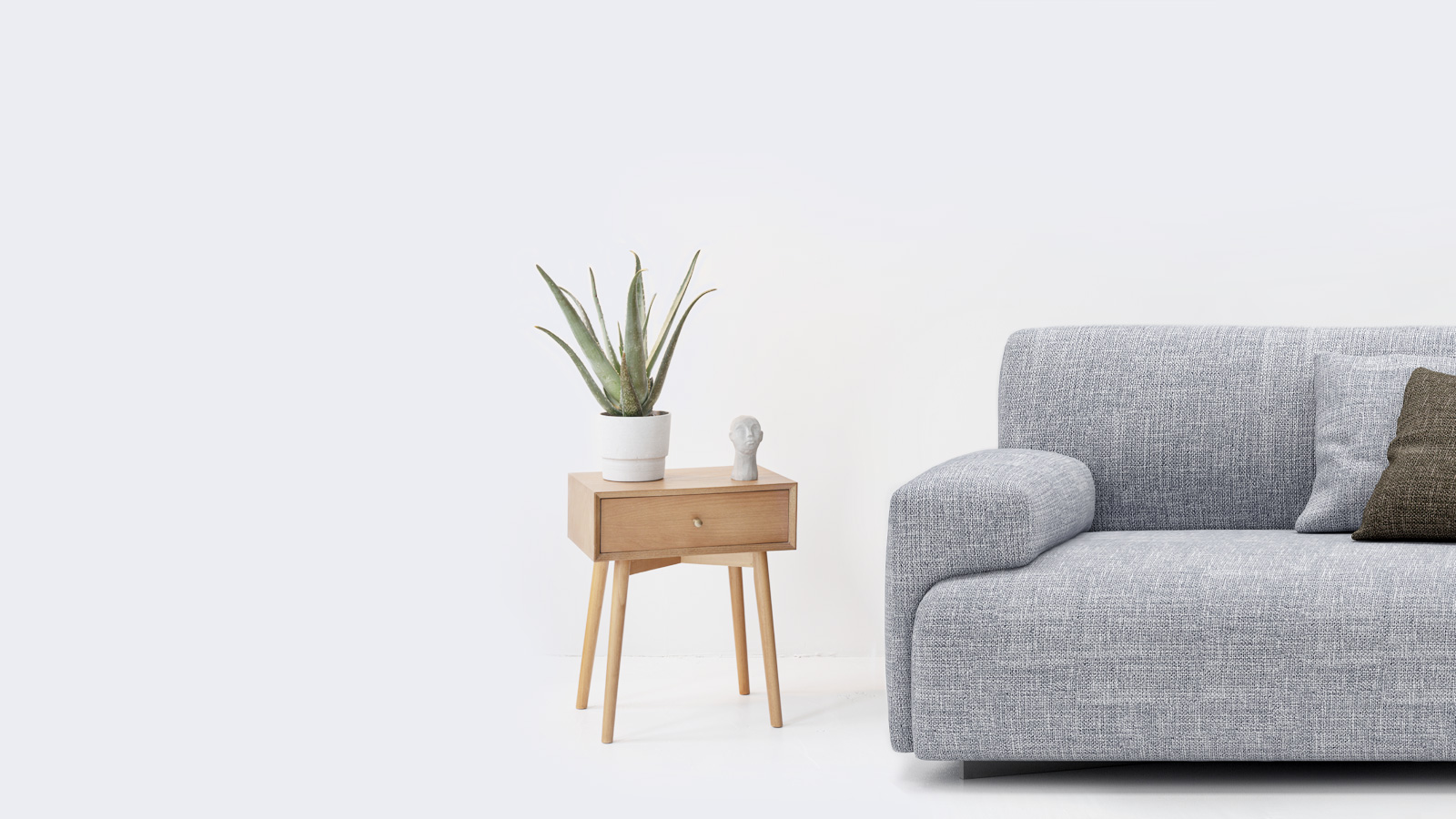 Sofá gris y planta frente a una pared blanca para Servicios jurídicos inmobiliarios